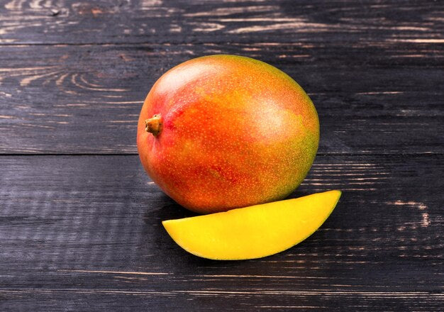 Ripe mango fruit and slice showing golden yellow flesh